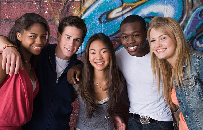 Group photo of young adults posing together in front of a colorful wall