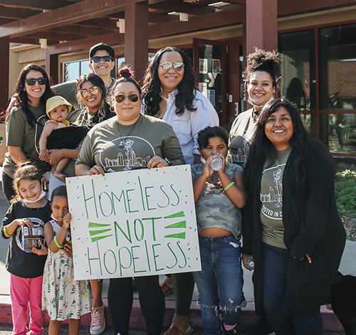 Photo of ladies holding a sign that says "Homeless not Hopeless"