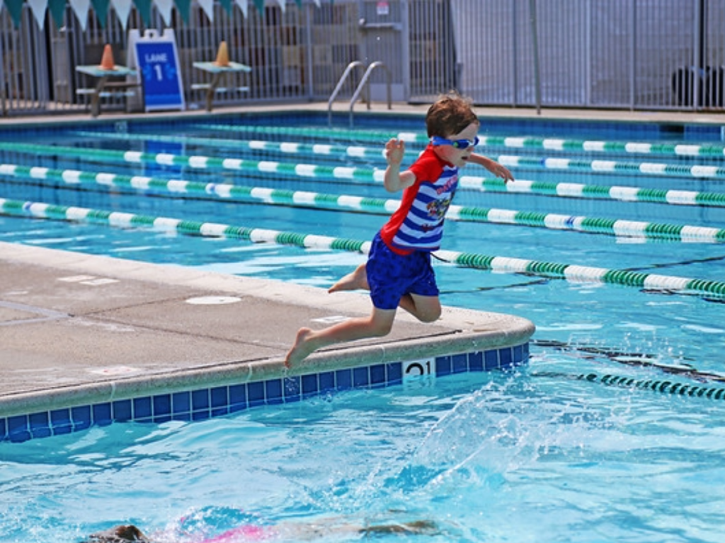 Photo of a kid jumping into a swimming pool