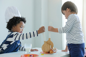 Photo of two children pretending to prepare food