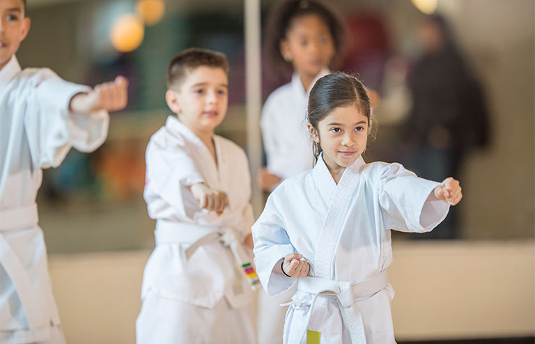 Photo of three children practicing martial arts wearing their gi