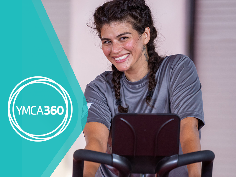 Photo of a woman working out on the cycle next to the YMCA360 logo