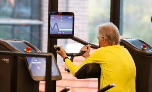 Man with yellow doing bicep curls on an egym machine