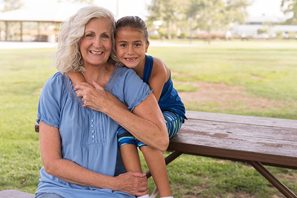 Photo of a girl sitting on a bench holding her grandmother