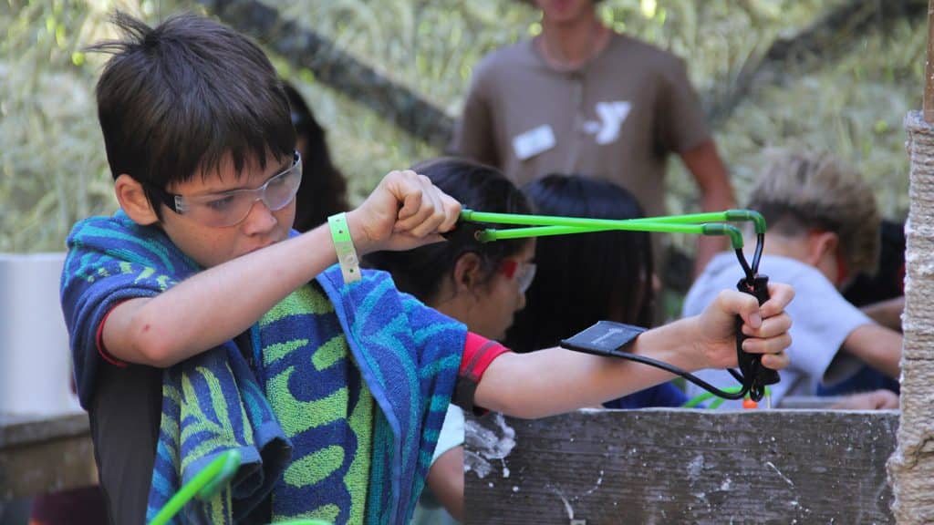 overnight camp boy with slingshot