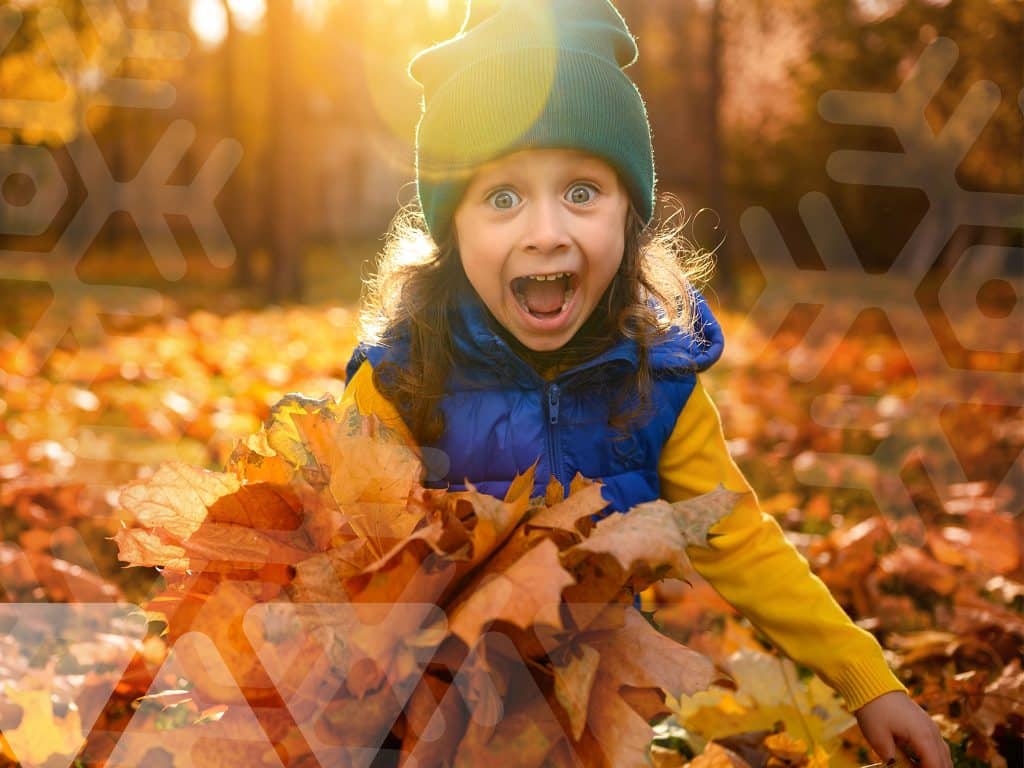 child playing in fall leaves
