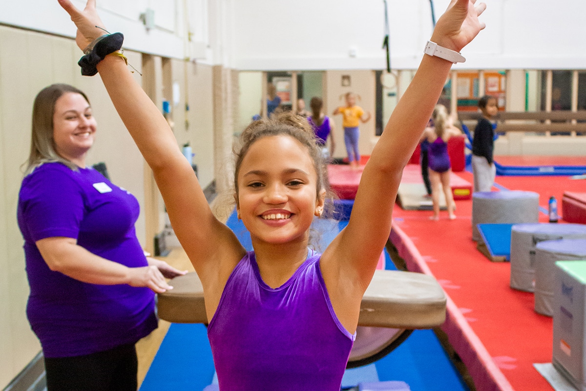 girl with arms up after gymnastics trick