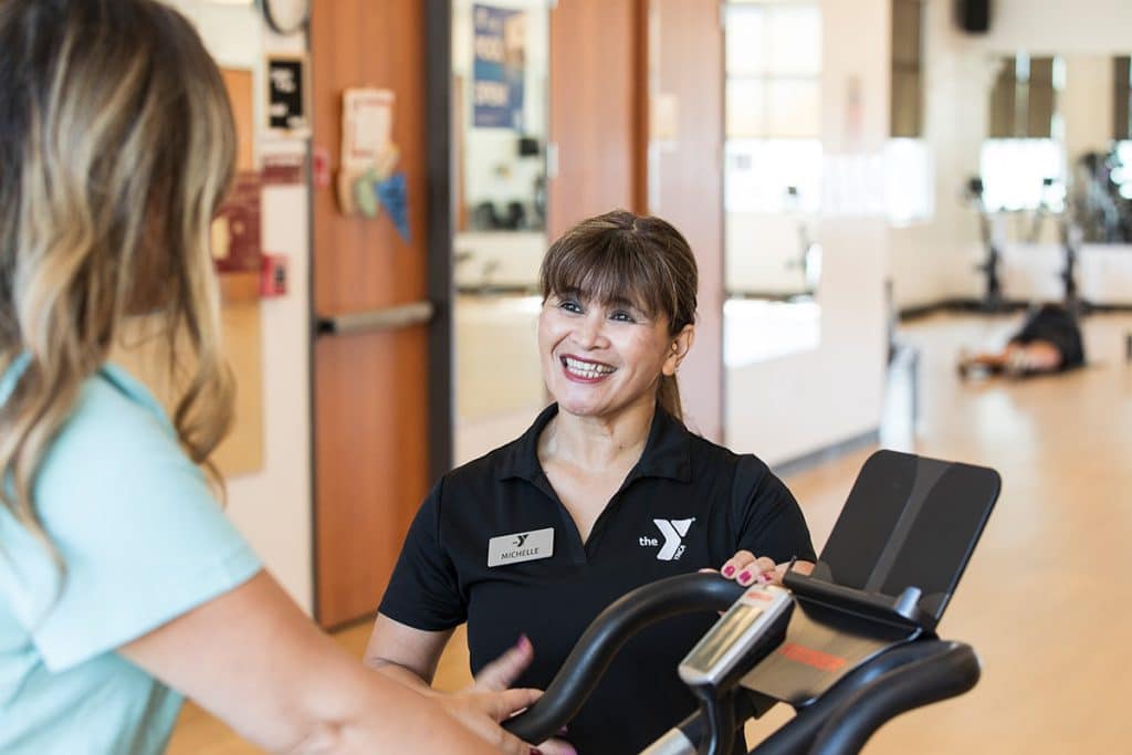instructor showing woman how to use fitness equipment